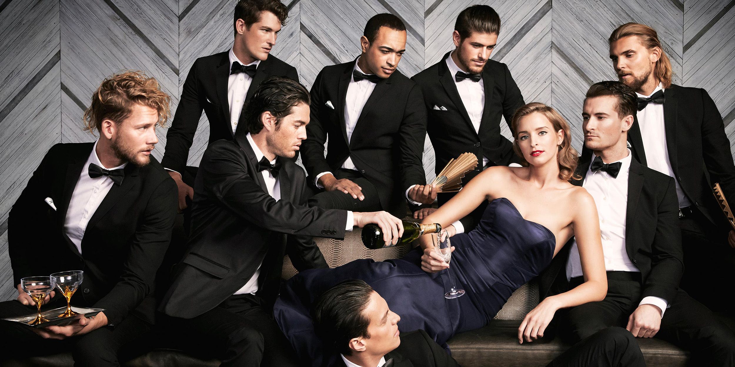 Woman in dress surrounded by many men in suits
