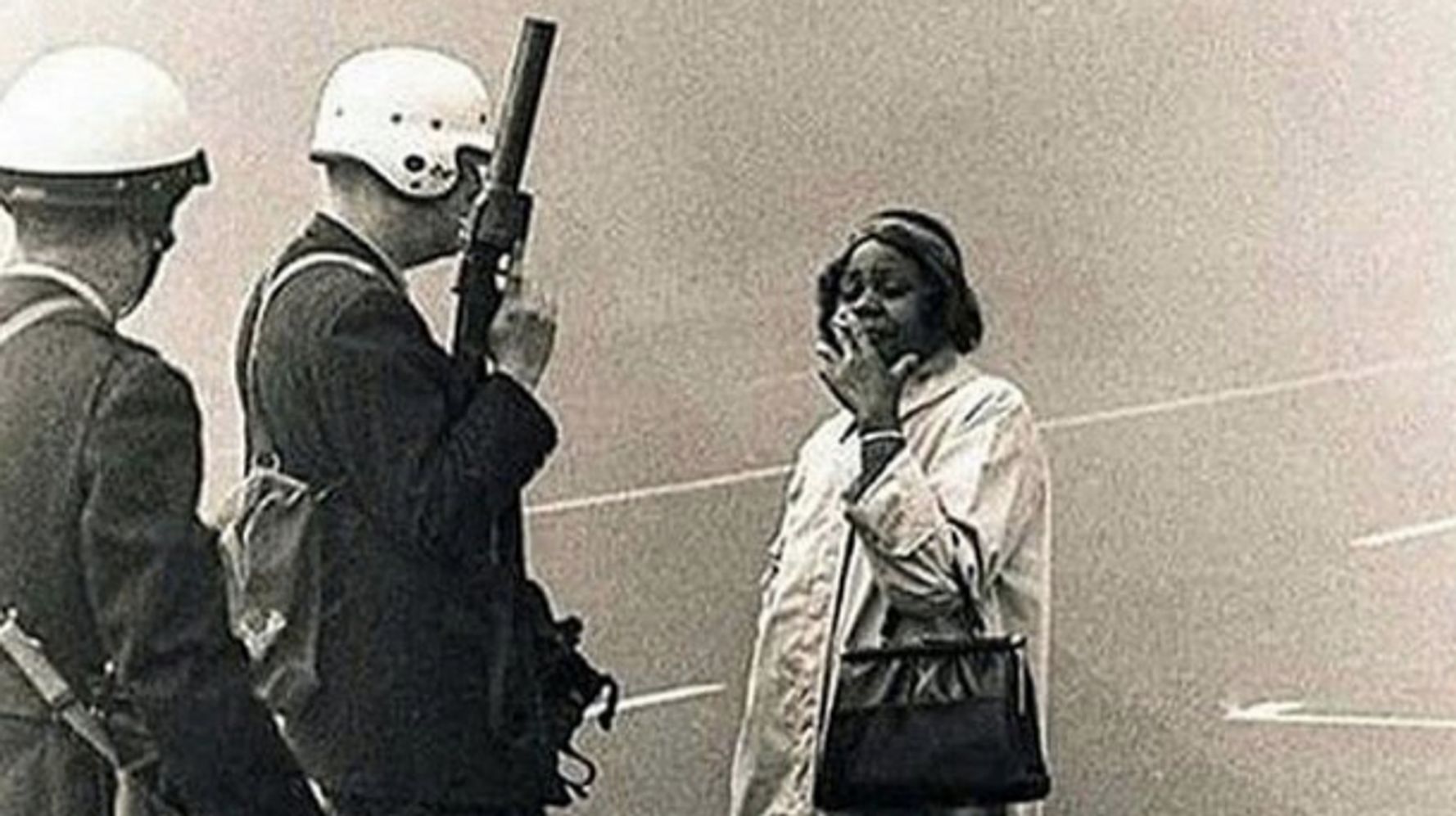 Old Black woman smoking cigarette in front of white racist police